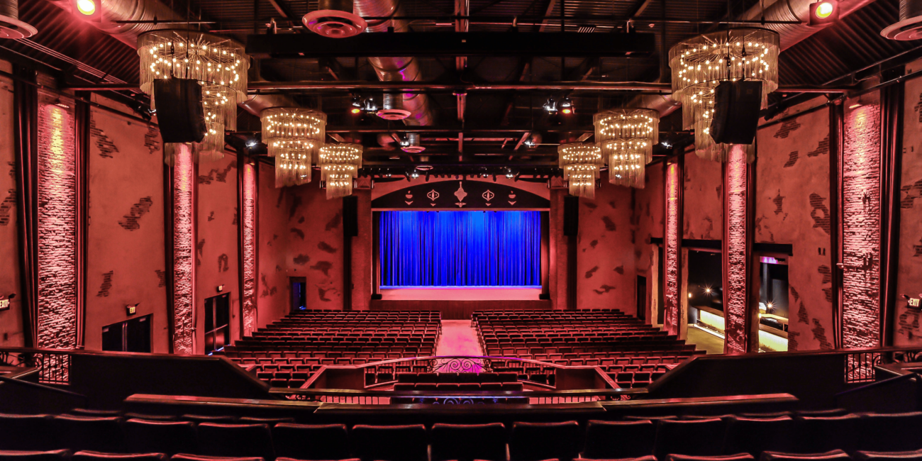 Image of Westbury theater. Taken from back of theater. Walls and seats of theater are velvet red.
