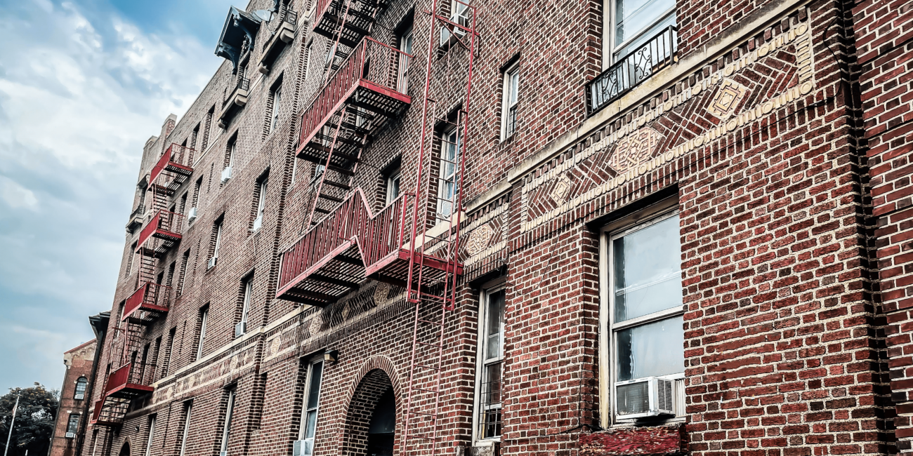 Image of red brick building. Fire escapes and windows shown.